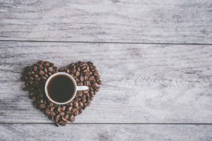 Kaffeetasse und ein aus Kaffebohnen geformtes Herz - Internationaler Tag des Kaffees